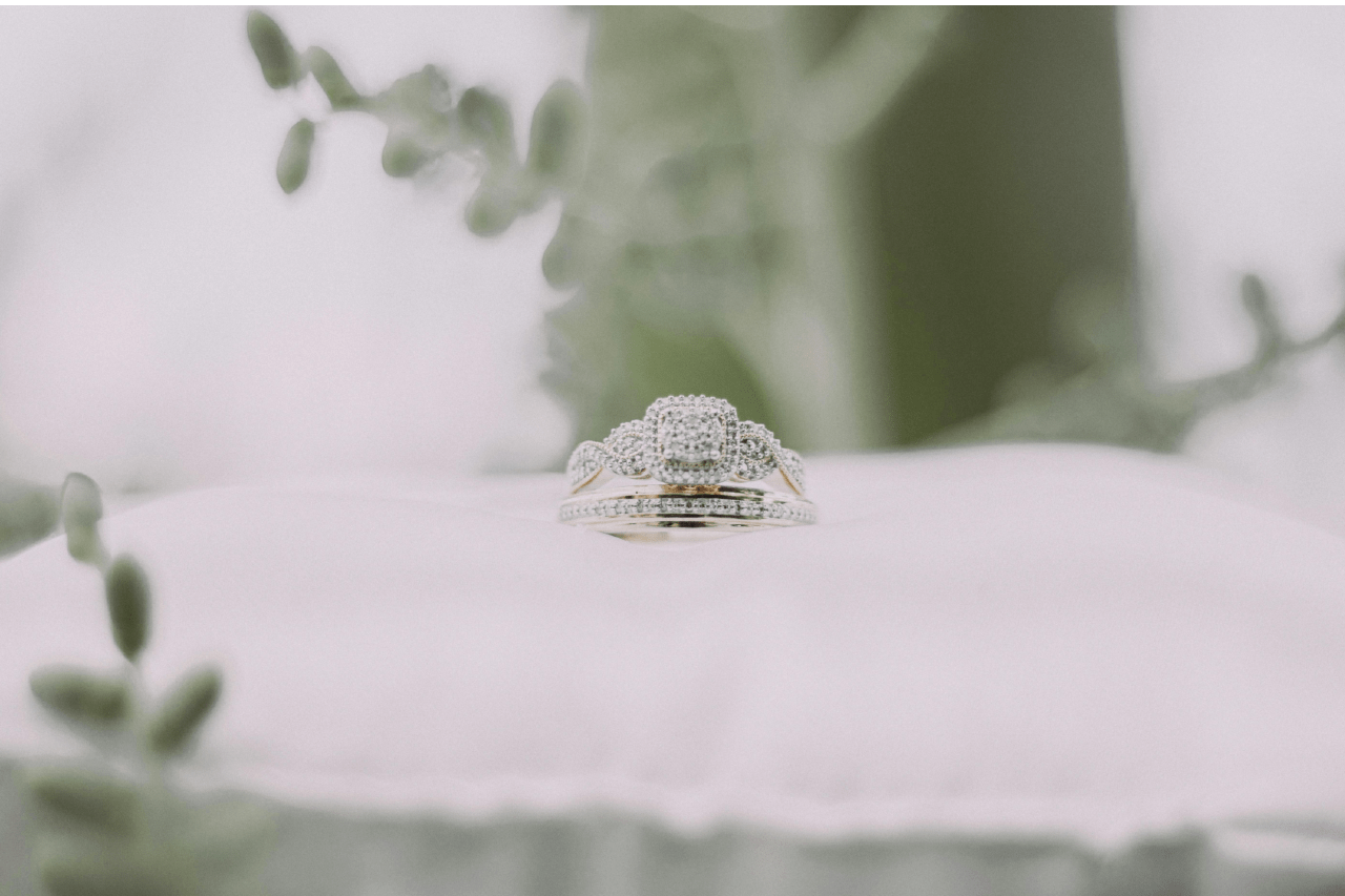 a vintage inspired engagement ring and wedding band sitting on a white pillow